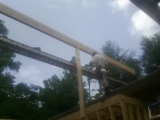 Carpenter setting a ridge beam over a new addition frame — Ice Dam Removal by Roofing Brothers in Baltic