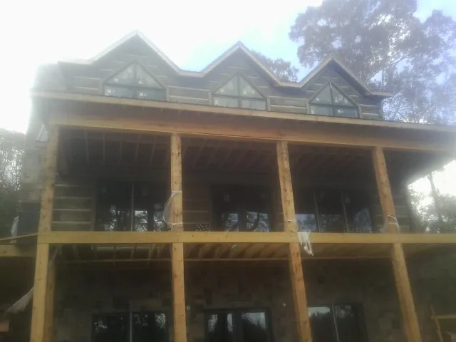 Dormers and porch framing on a large log home under construction — Roof Coating work by our crew in Baltic